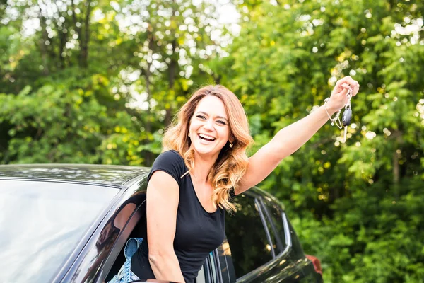 Autofahrerin mit Autoschlüssel fährt ihr neues Auto lachendes junges Mädchen — Stockfoto