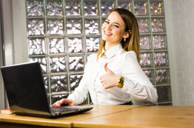 neşeli ofis çalışanı gösteren başparmak yukarıya laptop önünde