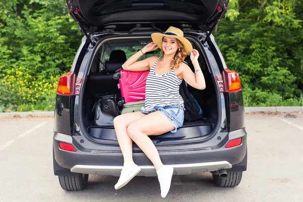 Mujer alegre en vacaciones de viaje de verano sentado en un maletero del coche . — Foto de Stock