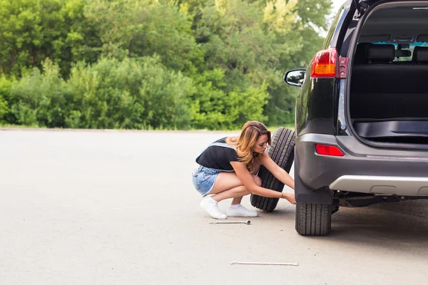 Sexy woman changing wheel on a roadside — Stock Photo, Image