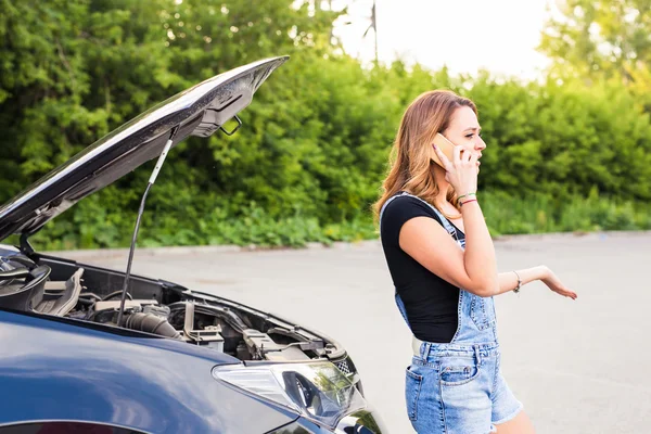 Mladá žena a rozbité auto, volání o pomoc na mobil. — Stock fotografie