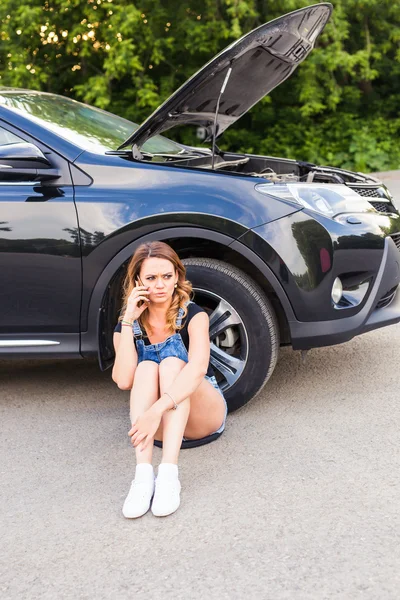 Mujer joven y coche roto pidiendo ayuda en el teléfono celular . — Foto de Stock