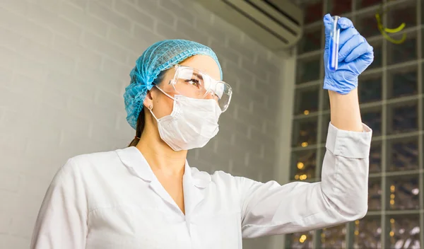 Скляна трубка з синьою рідиною в руці медсестри під час медичного тесту — стокове фото