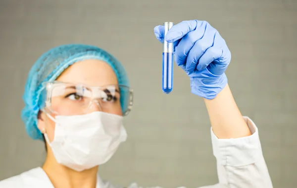 Närbild av glasrör med blå vätska i sjuksköterskans hand under medicinskt test — Stockfoto