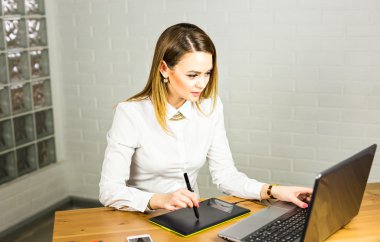 Genç kadın tasarımcı grafik tablet bilgisayar ile çalışırken kullanma
