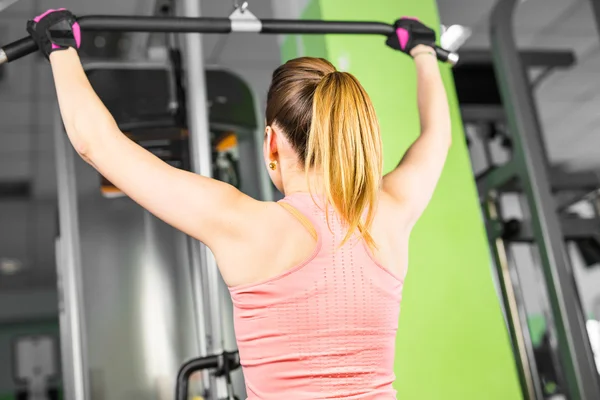Kvinnan skakar sina muskler på simulatorn i gymmet. — Stockfoto