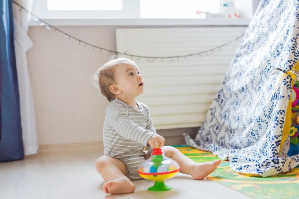 Liten pojke med en leksak som spelar på golvet hemma — Stockfoto