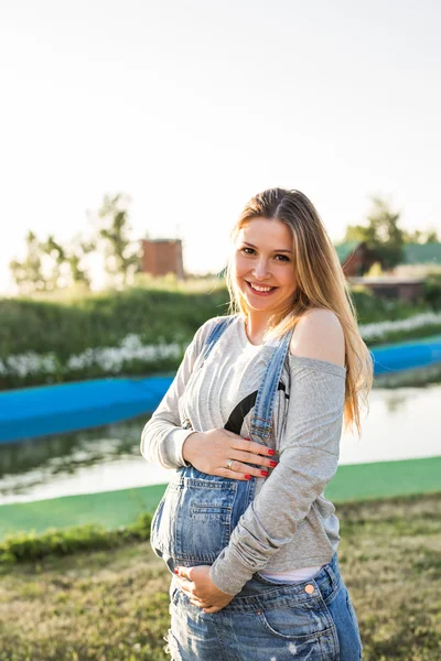 Gravid kvinna i parken, vidrör magen — Stockfoto