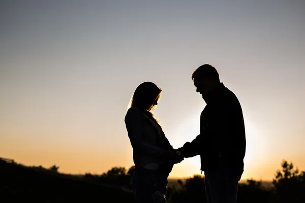 Silueta de una mujer embarazada con marido al atardecer — Foto de Stock