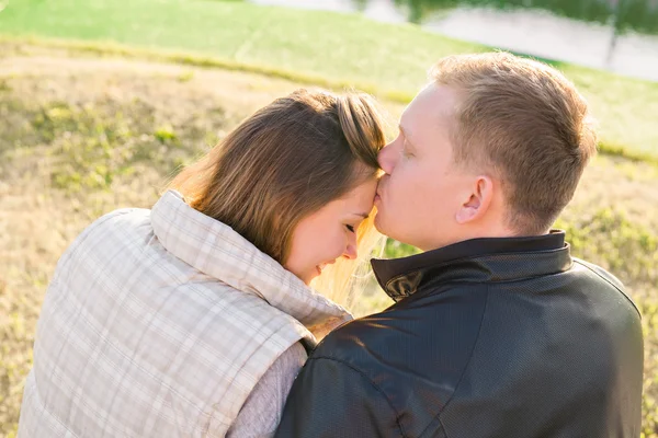 Молодая счастливая пара влюблена в романтический момент, когда мужчина целует свою жену в лоб под летним солнцем . — стоковое фото