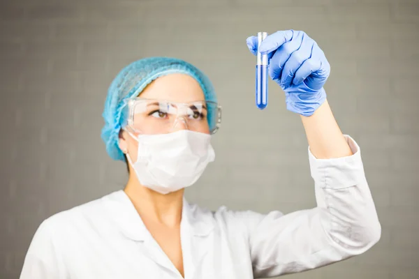 Γυναικεία ιατρική ή επιστημονική ερευνήτρια με ένα δοκιμαστικό σωλήνα διαυγούς διαλύματος στο εργαστήριο — Φωτογραφία Αρχείου