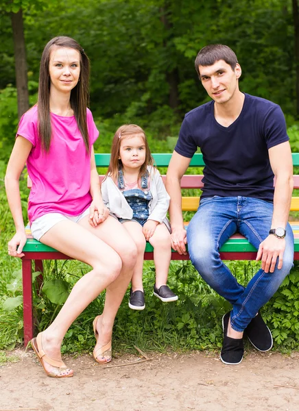 Junge Familie Mutter Papa Tochter sitzt auf einer Bank im Sommerpark — Stockfoto