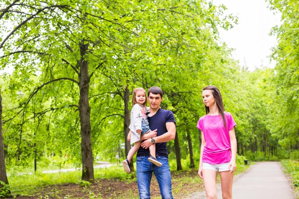 Feliz familia joven caminando por el camino fuera en la naturaleza verde — Foto de Stock