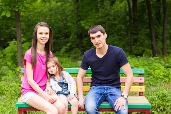 Rodina sedí na lavičce v parku — Stock fotografie