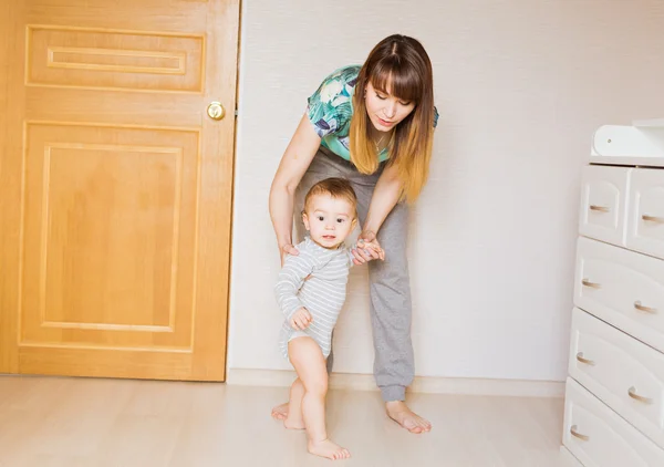 Baby macht erste Schritte mit Hilfe der Mutter — Stockfoto