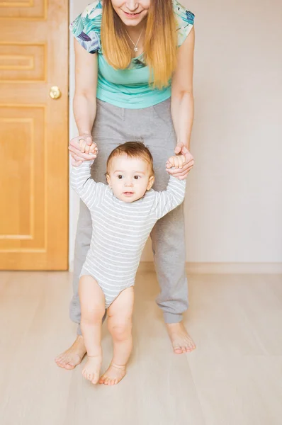 Baby macht erste Schritte mit Hilfe der Mutter — Stockfoto