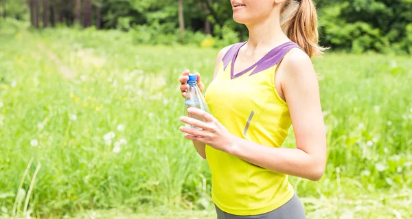 Fit femme à l'extérieur tenant une bouteille d'eau — Photo