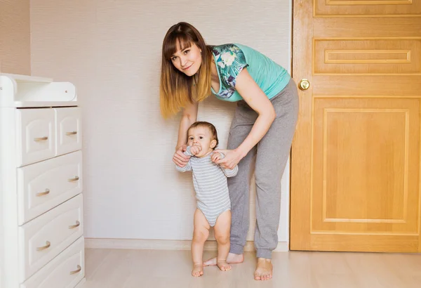 Niño pequeño primeros pasos con la ayuda de la madre — Foto de Stock