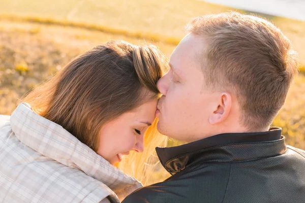 Ciuman manis. Tampan pemuda mencium pacarnya di dahi di musim gugur taman — Stok Foto