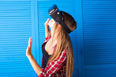 Sanal gerçekliğin video kulaklıklarını kullanan genç bir kadın el kol hareketleri yapıyor.
