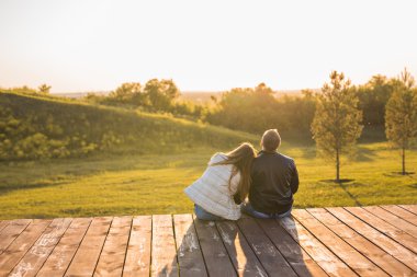 Romantik genç çiftin yakın bir kucaklama içinde oturan sonbahar doğanın keyfini görüntülemek arkadan