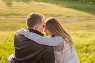 Romantik genç çiftin yakın bir kucaklama içinde oturan sonbahar doğanın keyfini görüntülemek arkadan
