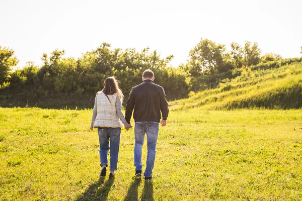 Vista trasera de pareja cogida de la mano caminando en otoño campo — Foto de Stock