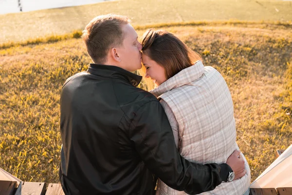 Jeune couple romantique jouissant de la nature automnale assis dans une étreinte étroite, vue de derrière — Photo