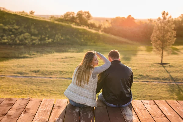 Romántica pareja joven disfrutando de la naturaleza otoñal sentada en un abrazo cercano, vista desde atrás —  Fotos de Stock