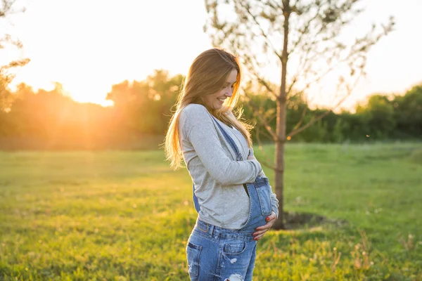 Молодая счастливая беременная женщина расслабляется и наслаждается жизнью в осенней природе — стоковое фото