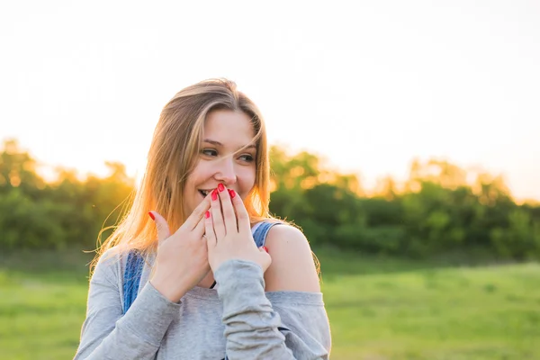 Překvapená mladá žena s rukama na ústech venku — Stock fotografie