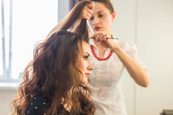 A hajsütővas segítségével a fürtök haj stylist kézzel közelről. — Stock Fotó