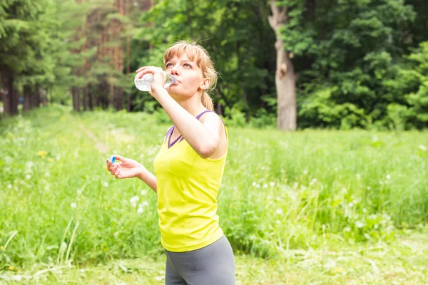 Jeune femme buvant de l'eau de bouteilles en plastique après le jogging. Perdre du poids. Mode de vie sain . — Photo