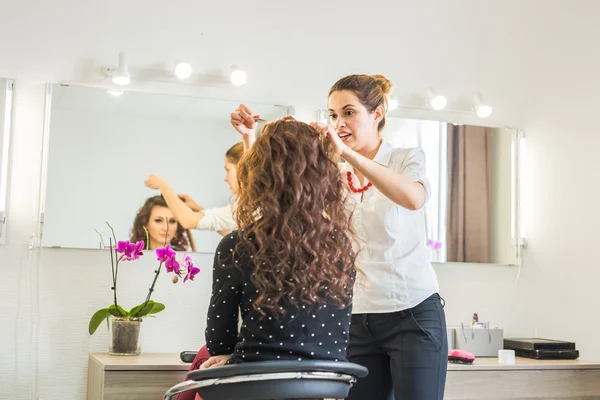 一个新的发型给女客户在客厅里的美丽年轻理发师 — 图库照片