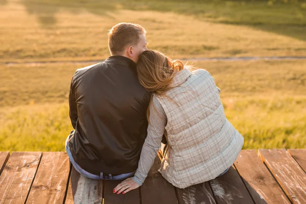 Romantiska par sitter på piren i höstens natur. — Stockfoto