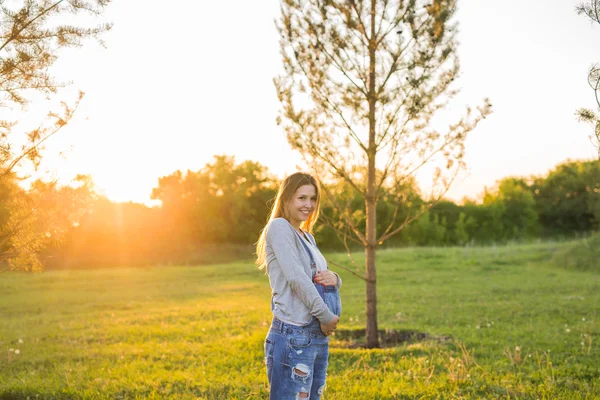 Fille enceinte en plein air sur un coucher de soleil — Photo