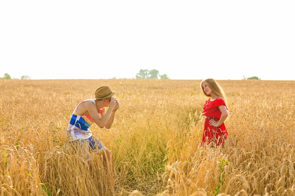 Fotógrafo con cámara tomando fotos de joven hermosa mujer en el campo . — Foto de Stock