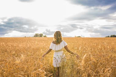 Kolları açık genç bir kadın güneşli yaz gününün tadını çıkarıyor.
