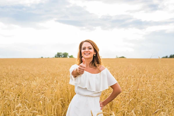 Hermosa mujer en un campo con los pulgares arriba — Foto de Stock