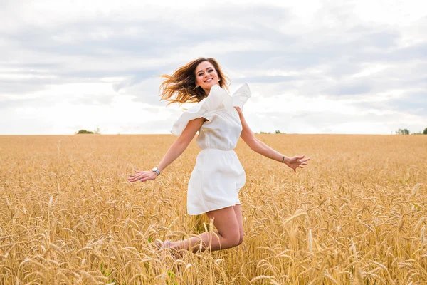 Mujer feliz saltando en el campo contra el cielo azul. Concepto de vacaciones y libertad —  Fotos de Stock