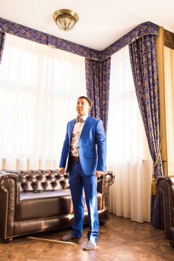 Zarif genç adam hazırlanıyor. Takım elbise, gömlek ve kelepçeleri giyinme.