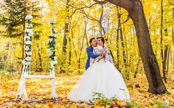 A noiva e o noivo em um balanço no parque de outono — Fotografia de Stock