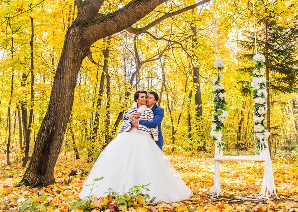 Gli sposi su un'altalena in parco di autunno — Foto Stock