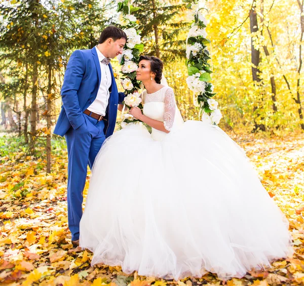 Bruden och brudgummen på en gunga i höst park — Stockfoto