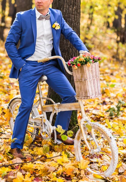 Knappe bruidegom en Vintage fiets met bloemen op herfst landschap-achtergrond — Stockfoto