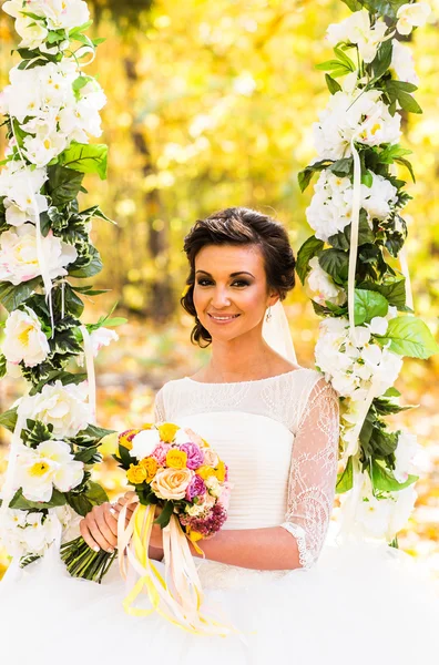 Prachtvolle Braut sitzt auf der Schaukel in einem herbstlichen Park — Stockfoto