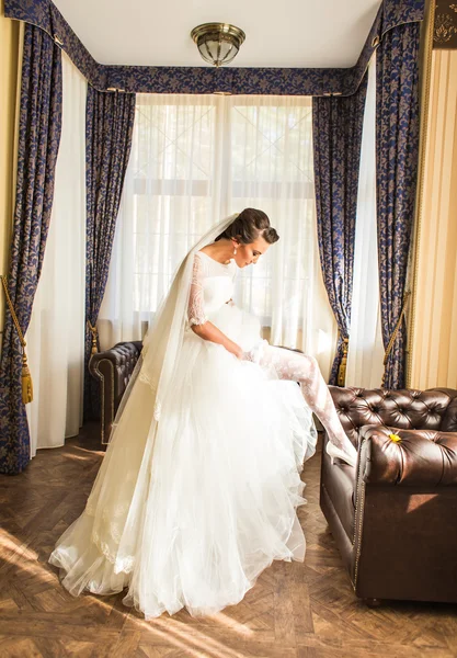 Schöne junge Braut mit Make-up und Frisur im Schlafzimmer, frisch vermählte Frau letzte Vorbereitungen für die Hochzeit. — Stockfoto