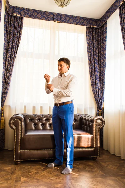 Happy gorgeous handsome groom getting ready dressed in the morning on background of a room — Stock Photo, Image