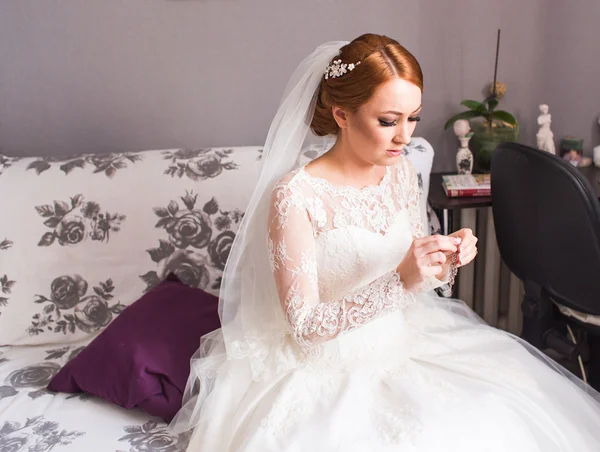 Elegante Braut setzt Ohrringe auf, bereitet sich auf die Hochzeit vor — Stockfoto