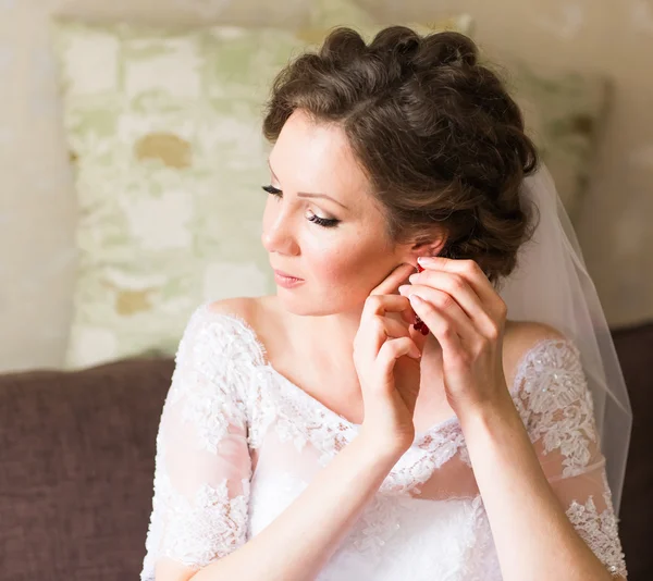 Noiva elegante vestindo brincos, se preparando para o casamento — Fotografia de Stock